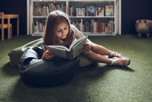 Écolierne lisant un livre dans la bibliothèque scolaire enfant engagé dans le livre apprendre et s'amuser curiosité de l'enfant