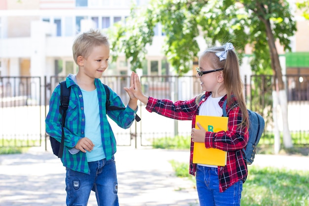 Les écoliers amis avec des sacs à dos saluent. écolier et écolière souriant