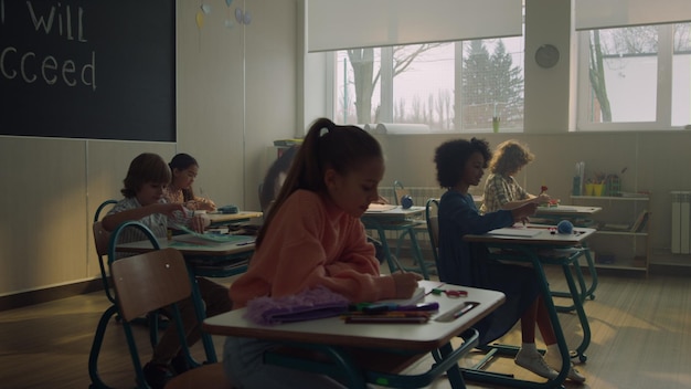 Des écoliers et des écolières étudiant dans une salle d'école. Des élèves assis à leur bureau.