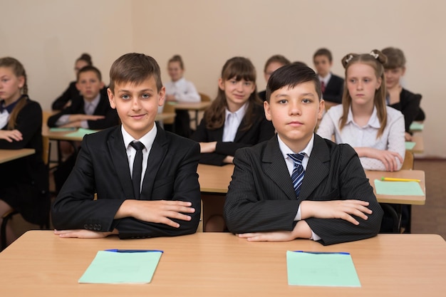 Des écoliers heureux s'assoient à un bureau dans la salle de classe