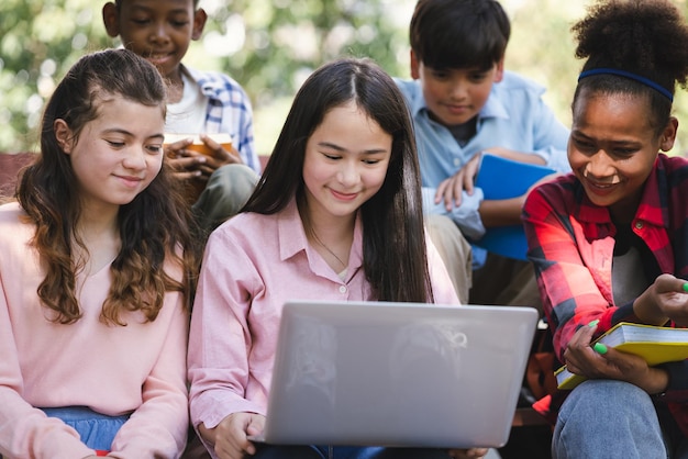 Les écoliers internationaux utilisent un ordinateur portable au parc de l'école