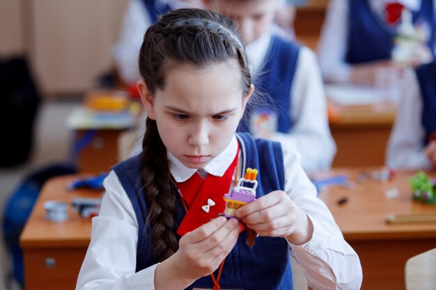 Les écoliers jouent dans des blocs en plastique de kit de construction lors d'une leçon à l'école primaire