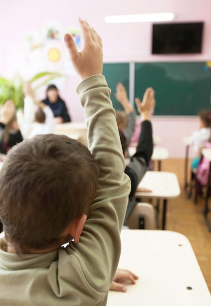 Écoliers avec la main levée dans la salle de classe