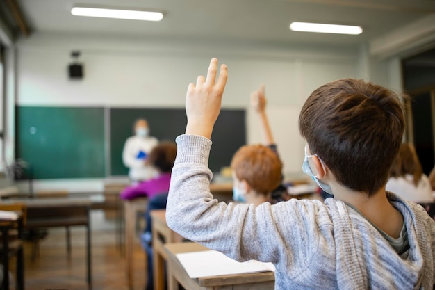 Des écoliers portant des masques faciaux en classe pendant la pandémie de covid-19.