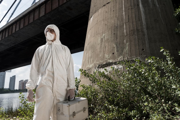 Écologiste en costume de protection avec kit d'inspection debout près du pont