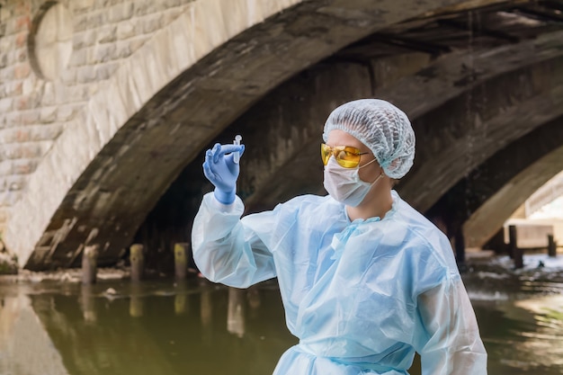 Une écologiste ou épidémiologiste examine avec anxiété un tube à essai avec de l'eau d'une rivière de la ville