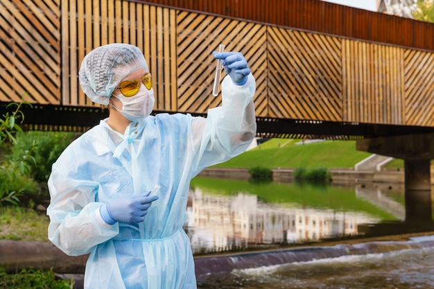 Photo Écologiste ou épidémiologiste féminin évalue visuellement la qualité de l'eau dans une rivière urbaine