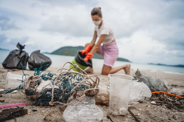 Une écologiste volontaire nettoie la plage au bord de la mer du plastique et d'autres déchets