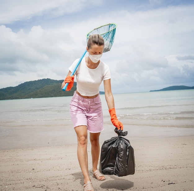 Une écologiste volontaire nettoie la plage au bord de la mer du plastique et d'autres déchets