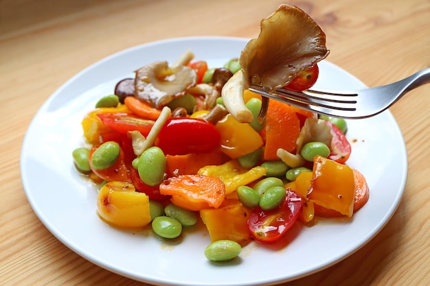 L'écopage à la fourchette de savoureux pleurotes indiens à partir d'un plat de salade de légumes grillés