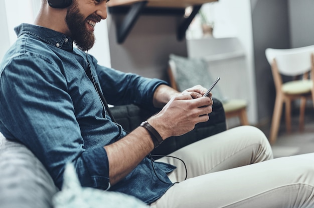 écouter de la musique préférée. gros plan sur un jeune homme tenant un téléphone portable et écoutant de la musique