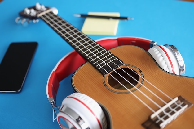 Les écouteurs mettent la guitare acoustique sur le plan rapproché bleu de fond