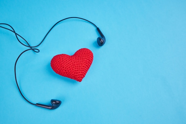 écouteurs noirs près de coeur rouge sur bleu avec espace de copie. amour au concept de rythme de musique