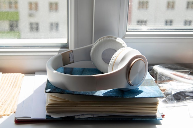 Des écouteurs sans fil blancs se trouvent sur le journal sur le rebord de la fenêtre