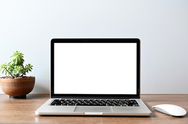 écran blanc ordinateur portable moderne avec souris, téléphone intelligent et succulent sur une table en bois dans l'arrière-plan de vue de bureau