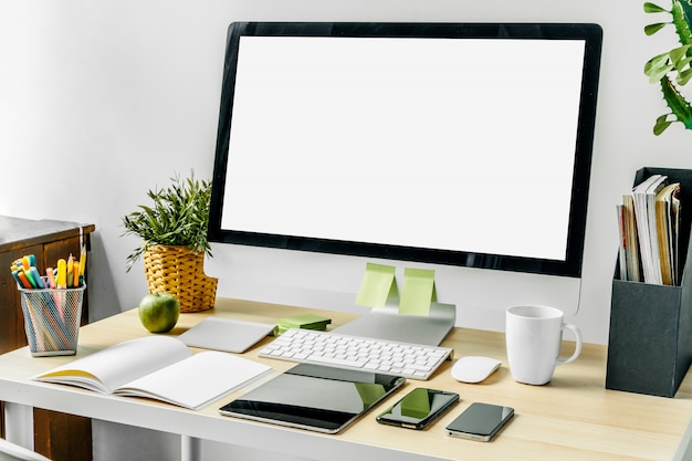 Photo Écran d'ordinateur avec écran blanc maquette sur la table de bureau avec des fournitures