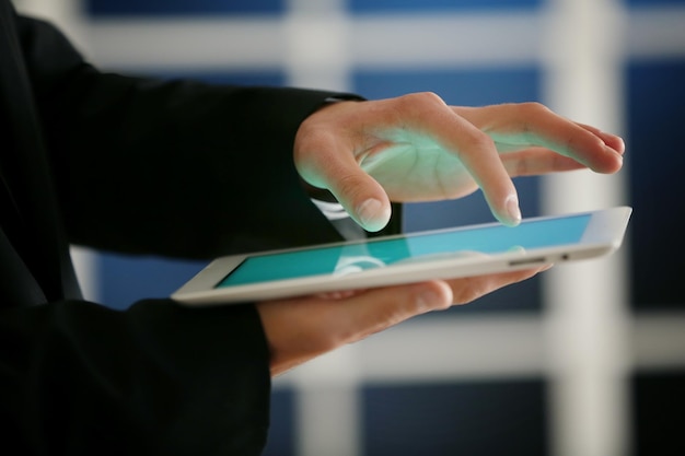 Écran de tablette tactile avec doigt masculin sur fond flou