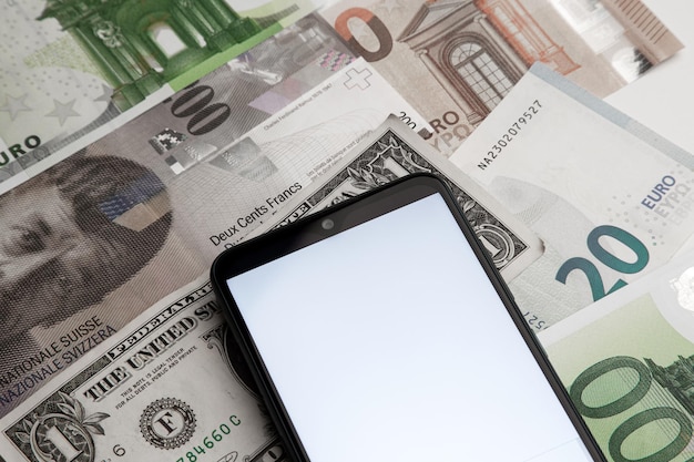 Un écran vierge de smartphone sur le fond de divers billets de banque