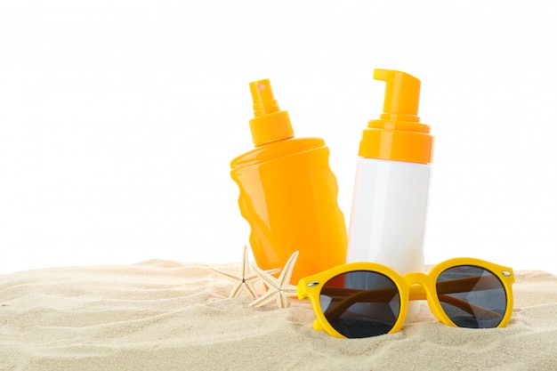 Écrans solaires avec étoile de mer et lunettes de soleil sur le sable de mer clair isolé sur fond blanc. Vacances d'été