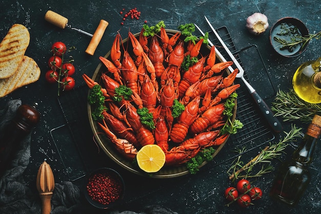 Écrevisses rouges bouillies avec des épices et des herbes dans un bol en métal. Vue de dessus. Mise à plat.