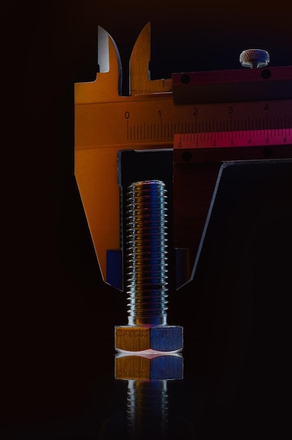 Écrous métalliques chromés de différentes tailles et un pied à coulisse mesurant l'écrou Fond noir