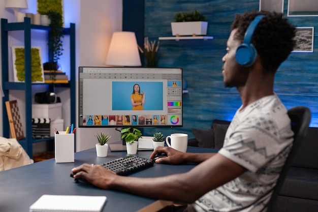 Éditeur afro-américain avec casque faisant des retouches sur des photos créatives