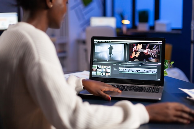 Photo Éditeur vidéo noir travaillant des heures supplémentaires sur un nouveau projet d'édition de montage de film audio assis dans un bureau d'entreprise en démarrage