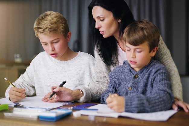 L'éducation commence à la maison Photo d'une mère aidant ses fils à faire leurs devoirs