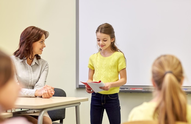 éducation, école primaire, apprentissage et concept de personnes - groupe d'écoliers avec enseignant en classe