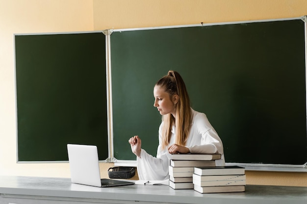 Éducation Écolière en train de taper sur un ordinateur portable et d'étudier en ligne à la commission scolaire Retour à l'école Fille avec des livres étudiant en ligne au tableau noir