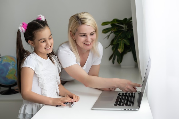 L'éducation en ligne des enfants. Mère et fille de la maternelle regardent une leçon vidéo appel de chat cours créatif dessin d'art en utilisant lapott à la maison.