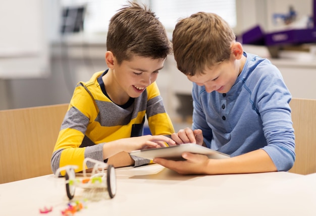 l'éducation, la science, la technologie, les enfants et les gens concept - garçons heureux ou étudiants avec tablette ordinateur programmation jouets électriques à la leçon de robotique à l'école