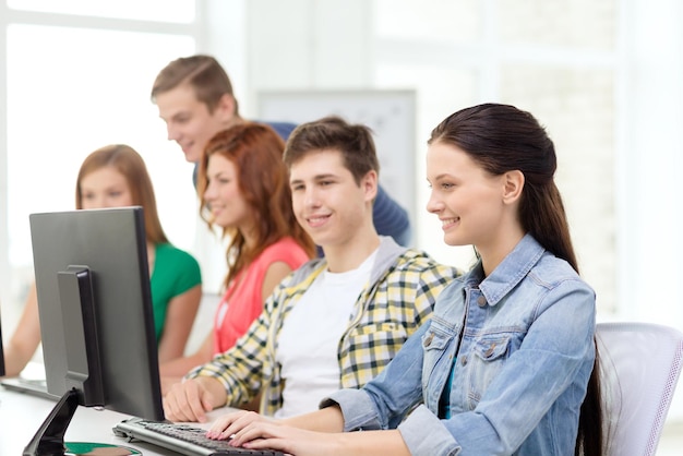 éducation, technologie et concept d'école - étudiante souriante avec des camarades de classe en cours d'informatique à l'école