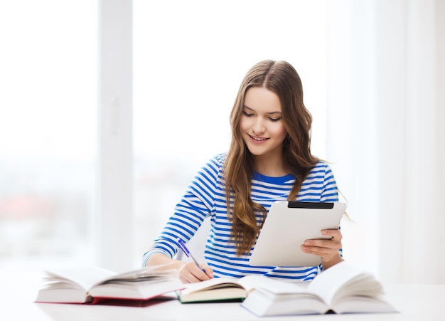 éducation, technologie et concept de maison - heureuse étudiante souriante avec ordinateur portable et livres à la maison