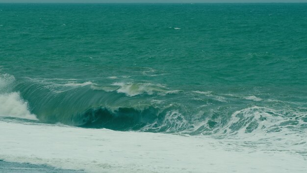 Effet du changement climatique vagues extrêmes de l'océan écrasant la côte géante brisant éclaboussé par le vent