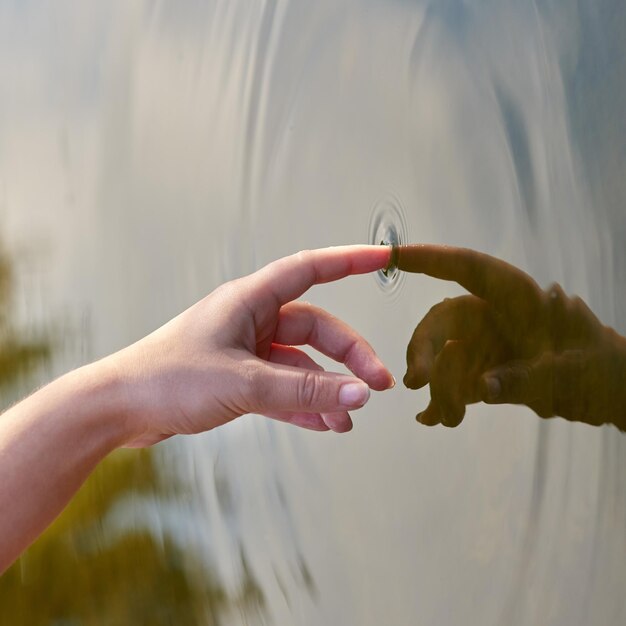 L'effet d'entraînement Photo recadrée d'un doigt touchant l'eau pour former des ondulations