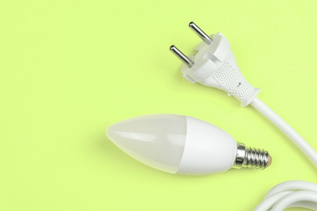 Efficacité énergétique verte avec ampoule LED et câble d'alimentation électrique avec prise UE. Fond vert, photo à plat et vue de dessus