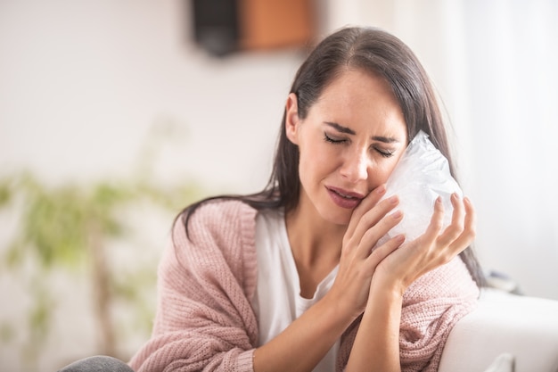 Un effort d'une fille pour soulager la dent douloureuse par un sac de glace à la maison.