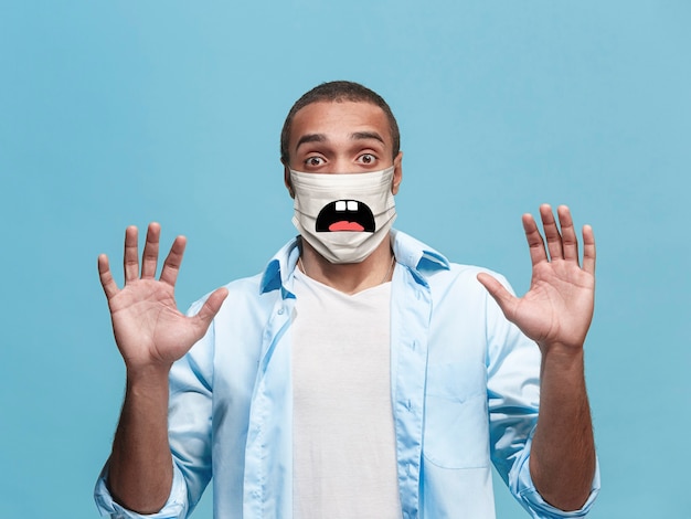 Photo effrayé, choqué. portrait de jeune homme afro-américain avec émotion sur son masque protecteur isolé sur fond de studio. beau modèle masculin. émotions humaines, expression faciale, concept publicitaire.