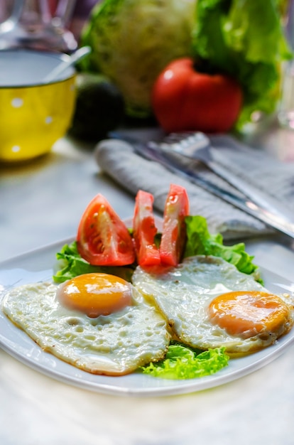 eggsufs frits de deux œufs sur une assiette avec tomate