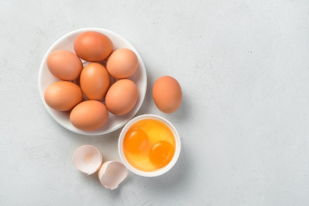 eggsufs de poule crus et jaunes d'œufs sur fond de béton gris. Vue de dessus, copiez l'espace.