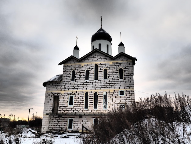 Une église avec des dômes sous un ciel dramatique Photo stylisée en noir et blanc ou sépia Nuages dramatiques sur l'édifice religieux en construction Sentiment d'horreur et de peur