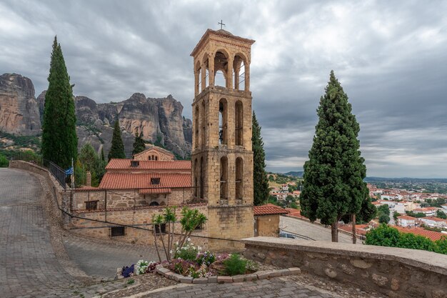 Une église avec un grand clocher élégant sur une colline devant d'énormes montagnes rocheuses au-dessus d'une ville