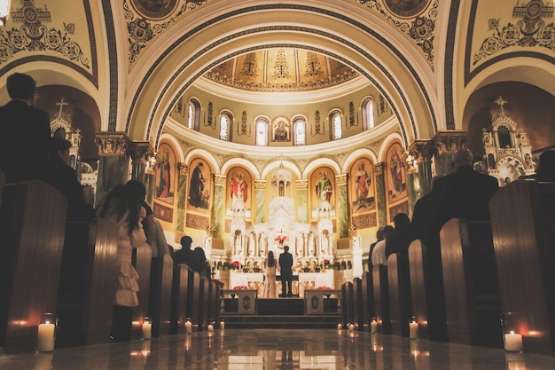 L'église de st. françois d'assise est décoré de cierges et d'un couple devant l'autel.