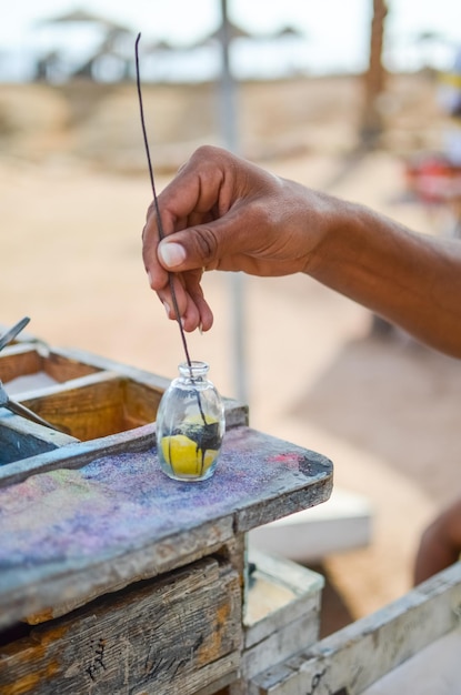 EGYPTE SHARM EL SHEIKH le vendeur sur la plage fait de beaux souvenirs faits de sable coloré