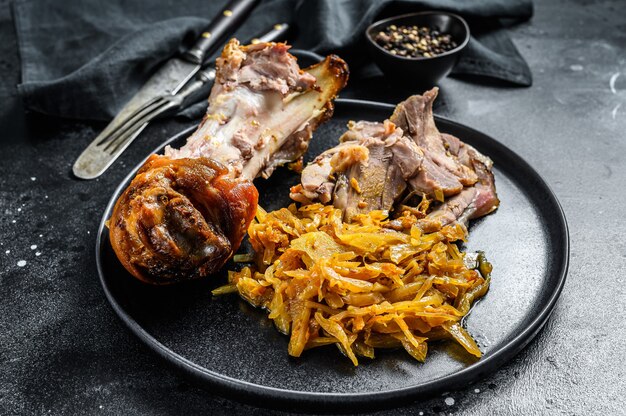 Eisbein de cuisse de porc au chou braisé. Fond noir. Vue de dessus.