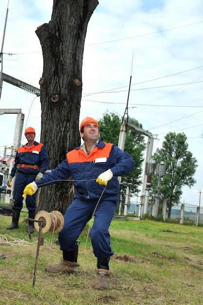 Un électricien essaie de mettre à la terre les fils d'une ligne électrique aérienne en lançant une charge