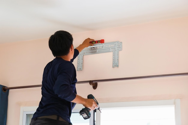 Électricien installant un climatiseur Réparateur réparant la climatisation Technicien installant un climatiseur dans une maison de client Concepts d'entretien et de réparation