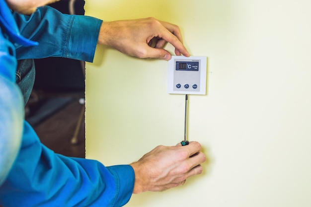 Électricien Installant Un Thermostat électrique Dans Une Nouvelle Maison.