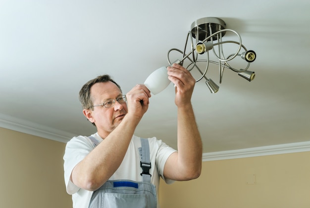 Un électricien installe et connecte une lampe